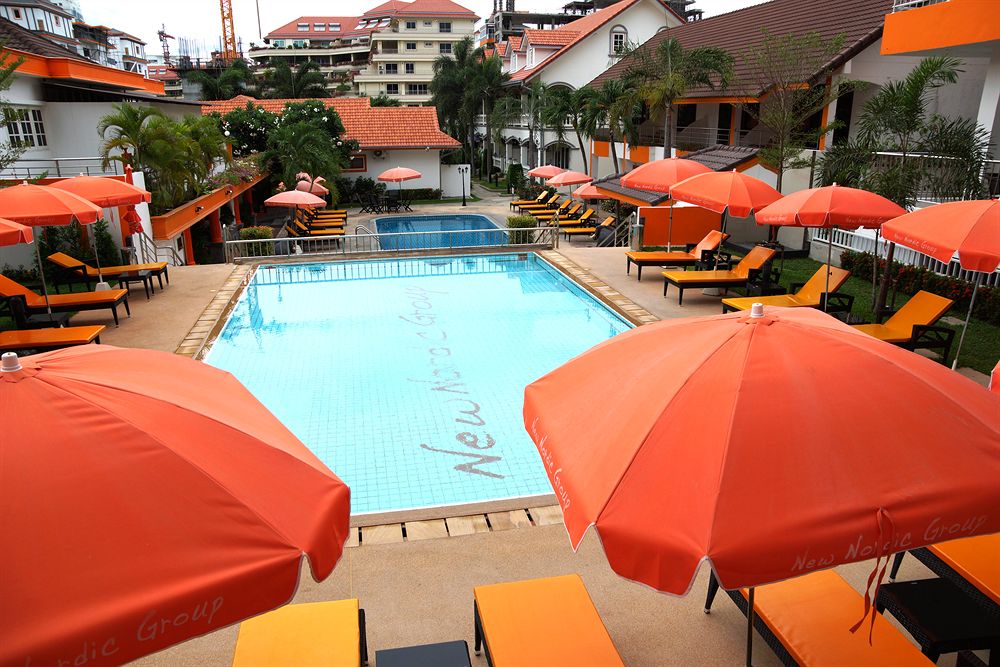 Swimming pool with orange umbrellas and loungers at a New Nordic property.